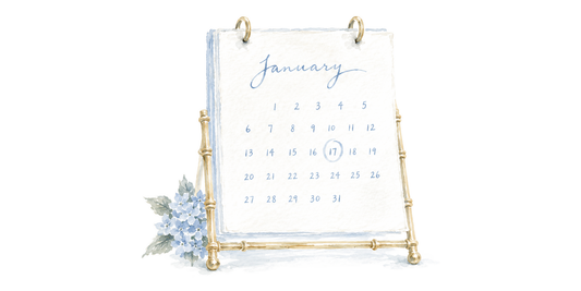 Watercolor of a January desk calendar on a gold bamboo stand, the 17th circled, with blue hydrangeas at its base