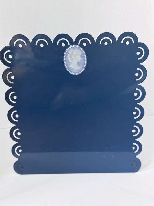 Cameo Needleminder Board in navy with scalloped eyelet edge and a pale blue pearl-edged cameo at the top, a tapestry needle in her chignon