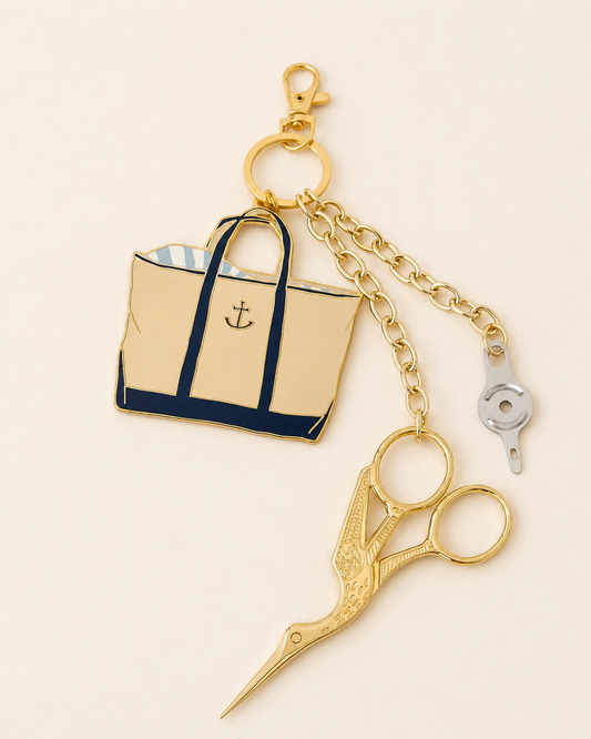 Sara Fitz canvas tote enamel charm on a gold chain with gold stork embroidery scissors and a needle threader